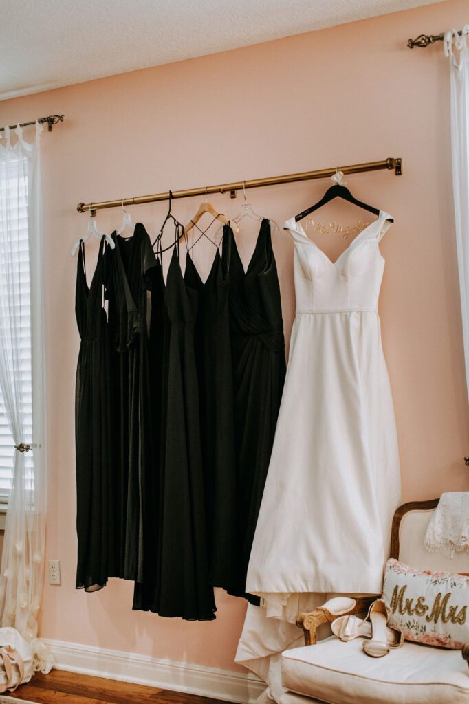 white wedding dress and black bridesmaid dresses hanging in a bridal suite at The Heartland Lodge